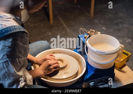 maître de classe sur la sculpture d'un pot dans un atelier d'art. la fille derrière la roue de potier fait un blanc avec ses mains. Banque D'Images