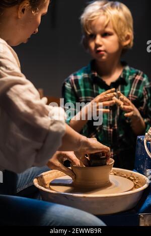 une leçon de poterie à une école d'art est enseignée par une jeune fille un potier pour un enfant mignon. Banque D'Images