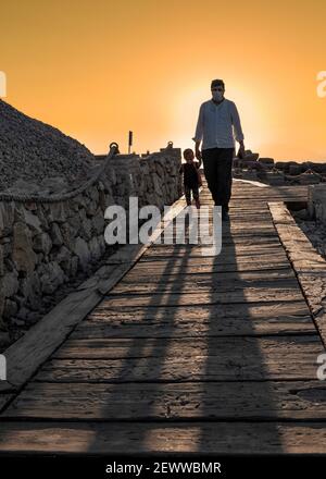 Kahta, Adiyaman, Turquie - septembre 14 2020: Père touristique et sa fille marchant sur le sentier autour de la montagne Nemrut et coucher de soleil en arrière-plan. Banque D'Images