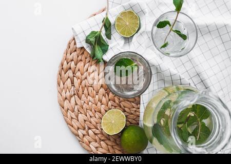 Détoxiez l'eau avec des fruits à la chaux et des feuilles de menthe dans un pot et des verres. Flat lay, vue de dessus Banque D'Images