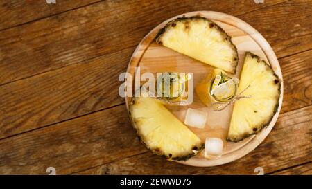 Jus d'ananas frais avec glace dans un petit verre bouteille sur fond de bois Banque D'Images
