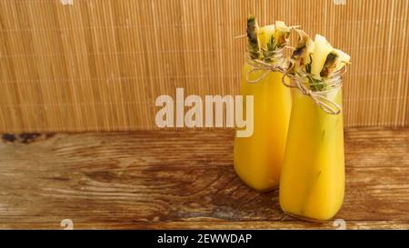 Jus d'ananas dans une petite bouteille. Des tranches d'ananas décorent la boisson Banque D'Images