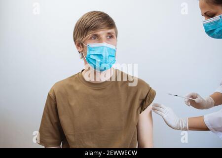 Un homme reçoit le vaccin Covid-19. Gros plan médecin faisant l'injection au patient dans le masque médical. Seringue de vaccin contre le coronavirus. L'homme reçoit la vaccination de jab Banque D'Images