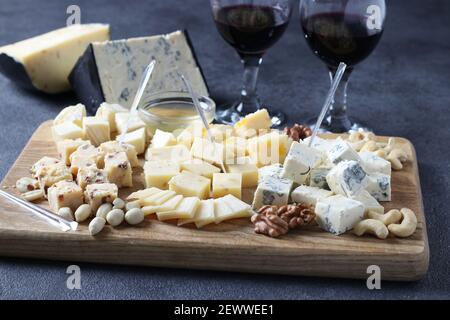 Fromages d'élite : avec truffe, bleu d'or, brie, parmesan et assortiment de noix sur une planche de bois. Apéritif pour une fête au vin. Gros plan Banque D'Images