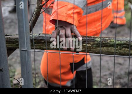 Old Oak Lane, Londres, Royaume-Uni. 3 mars 2021. HS2 ouvrier de construction derrière une clôture s'est installé autour du camp des activistes. Dans la nuit du 2 au 3 mars, un groupe d'écologistes a mis en place un camp de protection pour arrêter les travaux du HS2. Les exfoliants de bois de millepertuis sont une réserve naturelle locale désignée (LNR) protégée en vertu de la Metropolitan Open Land Act de 1879. Les sections locales affirment que le HS2 a « tranquillement fait passer des propositions de planification pour commencer des travaux de construction et des tunnels de 24 heures afin de détourner la ligne d’égout de Stamford Brook à travers les exfoliations de Wormwood ». Sabrina Merolla/Alamy Banque D'Images