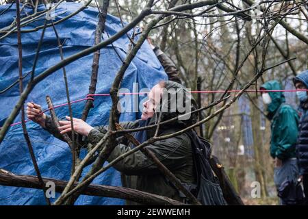 Old Oak Lane, Londres, Royaume-Uni. 3 mars 2021. Un résident local aide les militants à construire un refuge de nuit contre la pluie. Dans la nuit du 2 au 3 mars, un groupe d'écologistes a mis en place un camp de protection pour arrêter les travaux de construction de HS2 dans la réserve naturelle de Wormwood Scrubs, une réserve naturelle locale (LNR) protégée en vertu de la loi Metropolitan Open Land Act de 1879. Les sections locales affirment que le HS2 a « discrètement fait passer des propositions de planification pour commencer des travaux de construction et des tunnels de 24 heures afin de dévier la ligne d’égout de Stamford Brook au travers des exfoliations de bois d’œuvre ». Sabrina Merolla/Alamy Banque D'Images