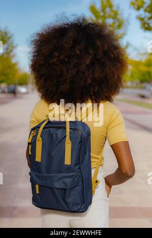 Vue arrière femme noire avec cheveux afro avec un sac à dos sur son dos Banque D'Images