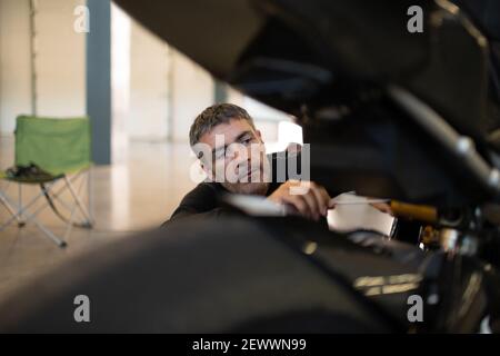 Homme concentré inspectant la moto dans le garage Banque D'Images