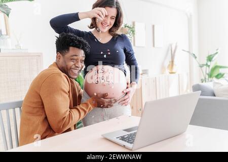 Mari et femme enceinte fêtant devant un ordinateur portable. Concept de planification familiale Banque D'Images