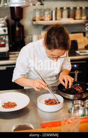 Le chef Michelin sert des plats sur les assiettes tout en travaillant dans le restaurant Banque D'Images