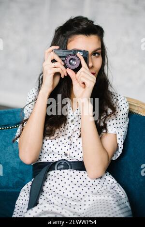 Jeune femme en robe rétro avec appareil photo sur gris toile de fond Banque D'Images