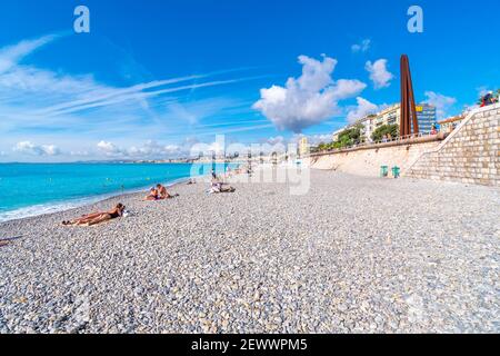 Les touristes se détendent sur la plage de galets de la Baie des Anges sur la Côte d'Azur à Nice, en France, un jour d'été. Banque D'Images