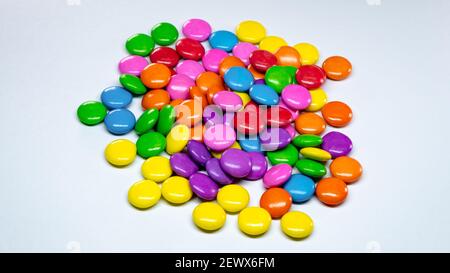 Mise au point sélective d'une pile de boutons de chocolat colorés sur fond de papier blanc. Banque D'Images