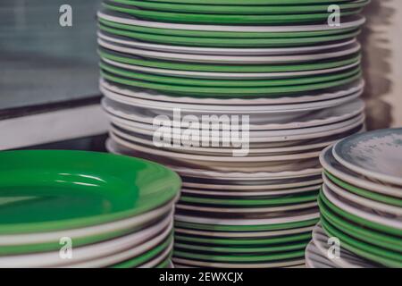 Gros plan stockage en pile de plastique de mélamine rond blanc vert nettoyer les plaques plates après lavage. Est-ce que cette cuisine vaisselle ustensiles mauvais, nocif Banque D'Images
