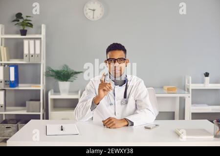 Jeune arfican sérieux homme américain docteur thérapeute gesticaling pendant la vidéo Banque D'Images