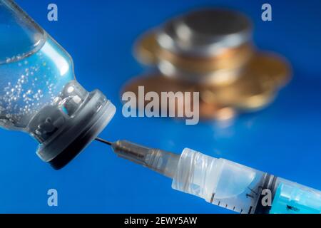 Production en studio de seringues, d'ampoules de vaccins et de pièces, sur fond bleu, au Brésil Banque D'Images