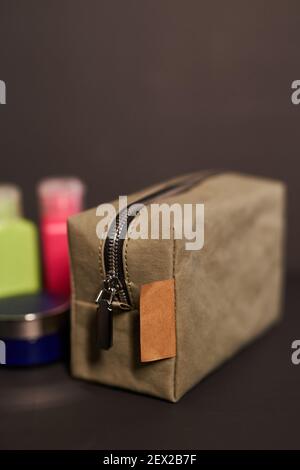 Sac à cosmétiques réutilisable en papier de voyage écologique avec jeu de couleurs bouteilles en plastique pour transporter des liquides dans un sac à bagages arrière-plan sombre Banque D'Images
