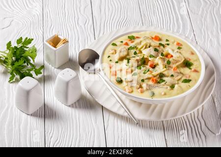 poisson poché dans une sauce à base de lait avec légumes, épices et herbes dans un bol blanc sur une table en bois, cuisine anglaise Banque D'Images