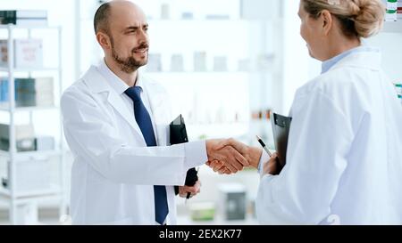 un pharmacien de sexe masculin se secouant la main avec son collègue. Banque D'Images