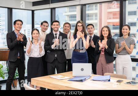 Un groupe d'affaires multiethnique se claque les mains de réussir après les affaires séminaire dans un bureau moderne dans le quartier des affaires Banque D'Images