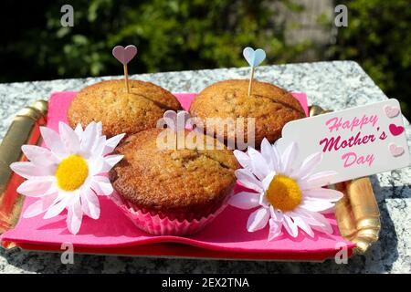 Magnifique plateau doré contenant 3 muffins pour la fête des mères. Avec des décorations, des pâquerettes, des coeurs et une carte de voeux Banque D'Images