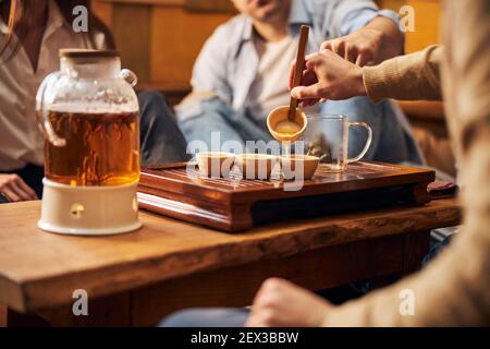 Un homme verse du thé à la main dans des tasses dans un café confortable Banque D'Images