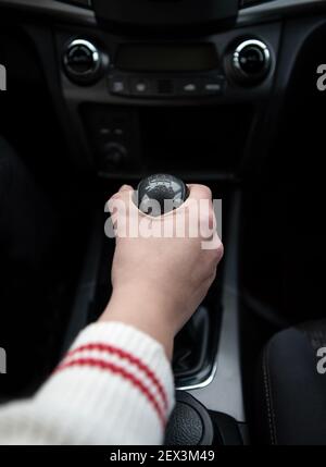 Personne qui change de vitesse avec le levier de changement de vitesse de la transmission d'une voiture. Intérieur du véhicule. Banque D'Images