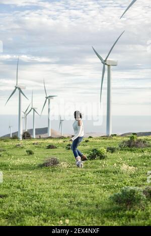 Vue latérale d'une femme insouciante qui court dans un champ avec des moulins à vent et jouer avec un adorable chien tout en appréciant le week-end d'été Lanzarote Banque D'Images