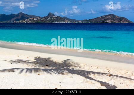 Ombre d'un palmier sur une plage des Caraïbes avec l'océan Turquoise des Caraïbes et l'île d'Union: Casuarina Beach, Palm Island, Saint Vincent et les Grenadines Banque D'Images