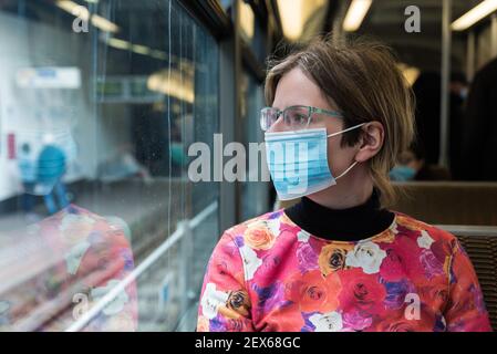 Belle femme de trente ans portant un masque buccal assis Sur le tramway de Bruxelles pendant les mesures COVID Banque D'Images