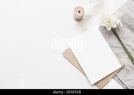 Photo stylisée. Printemps, composition de Pâques avec narcisse, jonquilles fleurs et serviette en lin isolée sur fond blanc de table. Espace vide Banque D'Images