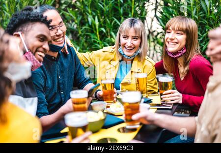 Les personnes multiraciales qui boivent de la bière avec masque ouvert - Nouveau concept d'amitié normale avec des amis s'amusant ensemble sur heureux heure à la brasserie Banque D'Images