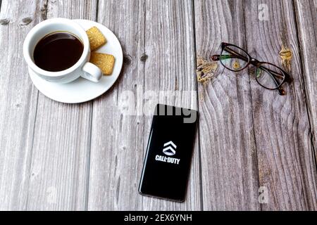 Un téléphone portable ou mobile posé sur un bois Avec l'application Call of Duty ouverte à côté de un café Banque D'Images