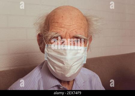 Vieil homme dans un masque médical de protection. Portrait. Grand-père caucasien dans le masque médical bleu. Concept de protection contre la grippe et les virus. Banque D'Images