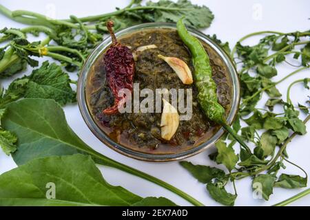 Curry indien maison Sarson ka saag ki sabji servi dans un bol transparent garni de frits de légumes verts, de légumes rouges et de gousses d'ail. Authentique non Banque D'Images