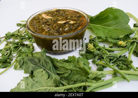 Curry indien maison Sarson ka saag ki sabji servi dans un bol transparent garni de frits de légumes verts, de légumes rouges et de gousses d'ail. Authentique non Banque D'Images