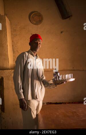 Maroc, Merzouga, portrait d'un serveur de thé, lumière de fenêtre éclairant un homme servant du thé Banque D'Images