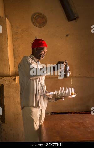 Maroc, Merzouga, portrait d'un serveur de thé, lumière de fenêtre éclairant un homme servant du thé Banque D'Images