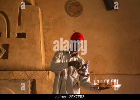 Maroc, Merzouga, portrait d'un serveur de thé, lumière de fenêtre éclairant un homme servant du thé Banque D'Images