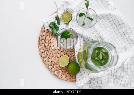 Détoxiez l'eau avec des fruits à la chaux et des feuilles de menthe dans un pot et des verres. Flat lay, vue de dessus Banque D'Images