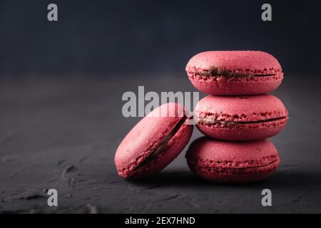 Macarons petits gâteaux français sur fond sombre. Dessert végétarien. Banque D'Images