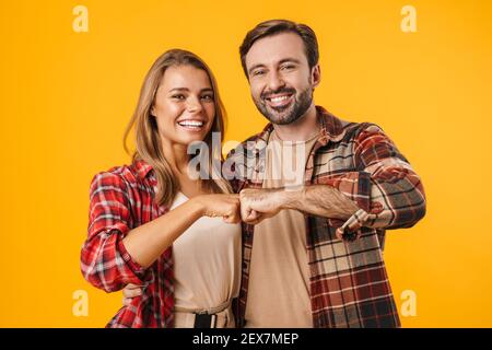 Beau couple heureux embrassant et poing bumping isolé sur jaune arrière-plan Banque D'Images