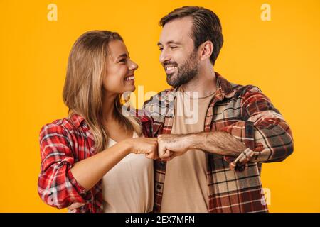 Beau couple heureux embrassant et poing bumping isolé sur jaune arrière-plan Banque D'Images