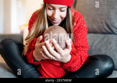 Photo de mère adorable tenant son bébé dans le canapé. Banque D'Images