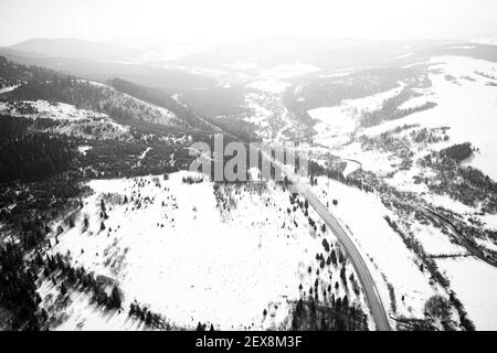 Vue aérienne sur la route de montagne depuis le drone en hiver. Image en noir et blanc Banque D'Images