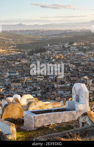 Paysage urbain coucher de soleil vue sur la médina de Fès avec des pierres tombales de cimetière en premier plan, tombes de Marinid, Fès, Maroc Banque D'Images