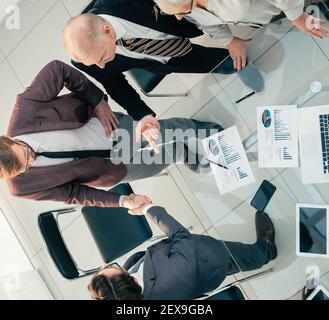 vue de dessus. les hommes d'affaires se secouent la main dans la salle de réunion. Banque D'Images