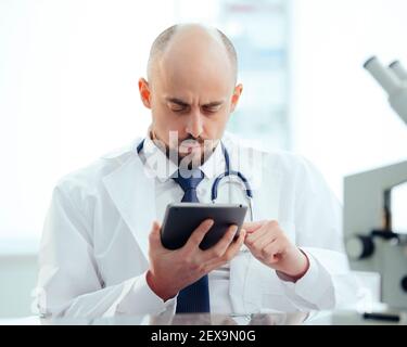 chercheur avec une tablette numérique assis à une table de laboratoire . Banque D'Images