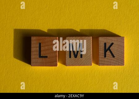 LMK, acronyme de dites-moi, en lettres de l'alphabet en bois isolées sur fond jaune Banque D'Images