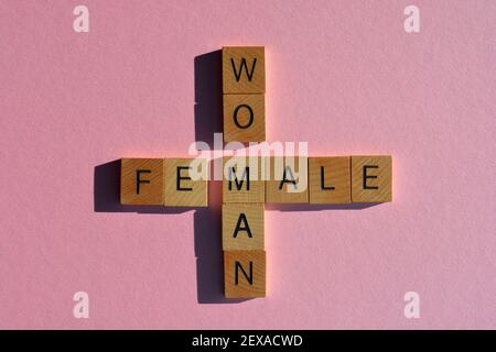 Femme, Homme, Femme, Homme, mots en lettres de l'alphabet en bois isolées sur fond rose Banque D'Images